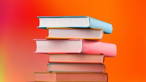 Stack of colorful heardcover books on an orange background